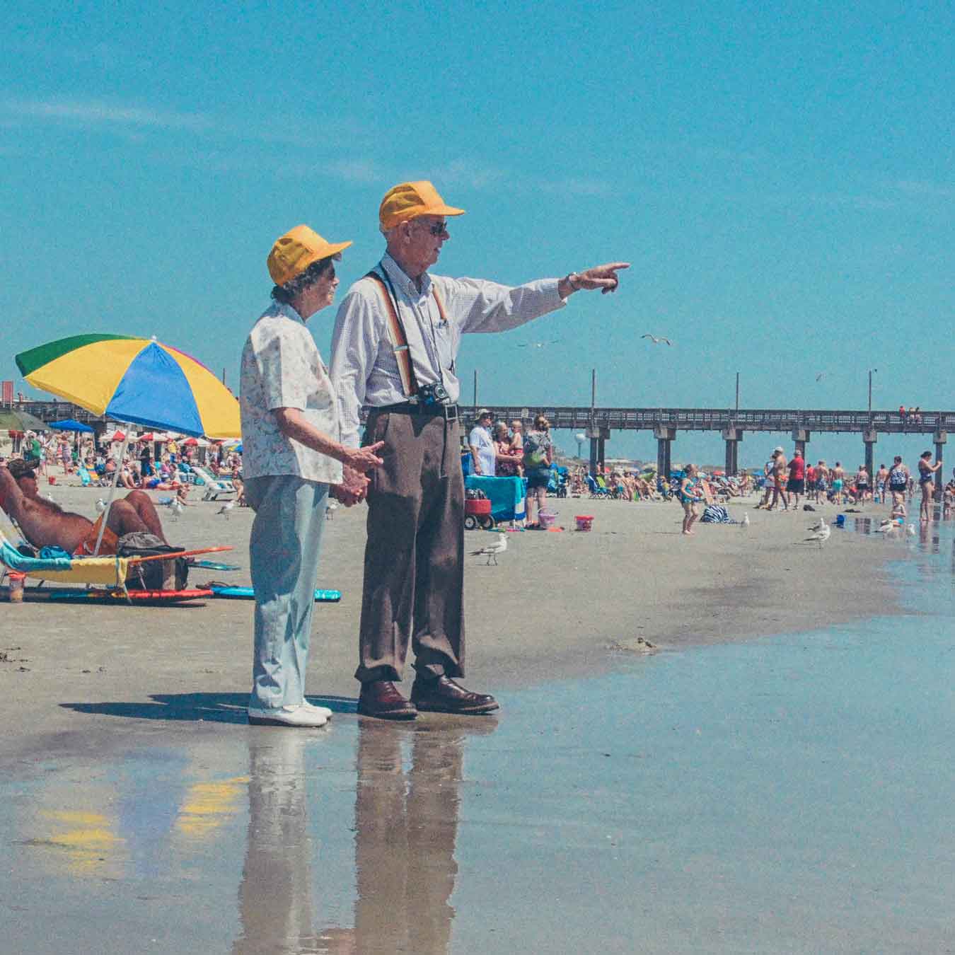 an elderly couple wearing matching yellow hats on the beach